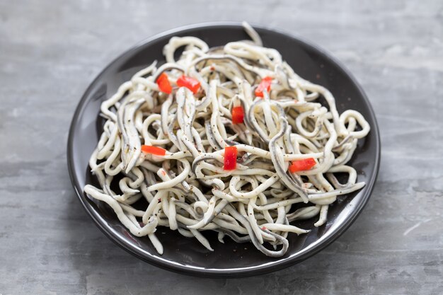 Comida tradicional espanhola. Gulas com óleo na chapa branca.