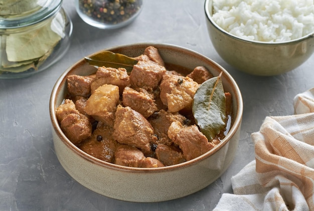 Foto comida tradicional filipina cerdo adobo vinagre de ajo salsa de soja arroz al vapor hojas de laurel mezcla de pimienta