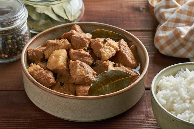 Foto comida tradicional filipina cerdo adobo vinagre de ajo salsa de soja arroz al vapor hojas de laurel mezcla de pimienta