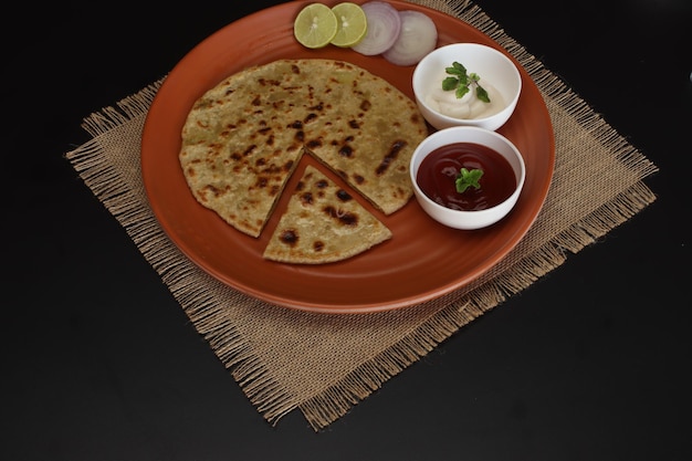 Comida tradicional india Aloo paratha o pan plano relleno de patata. servido con salsa de tomate