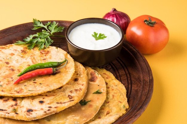 Comida tradicional indiana Aloo paratha ou pão achatado recheado de batata. servido com ketchup de tomate e requeijão sobre fundo colorido ou de madeira. Foco seletivo