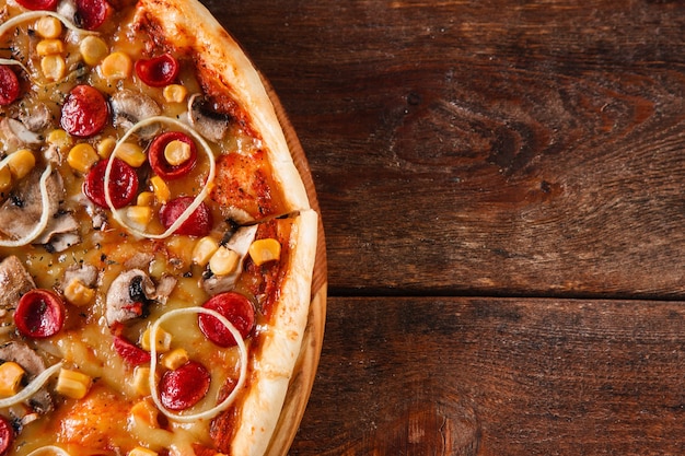 Comida tradicional italiana. Pizza apetitosa servida na mesa de madeira rústica. Fundo escuro com espaço de cópia.