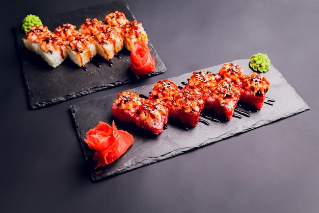 Comida tradicional japonesa Mezcle sushi colorido Conjunto de diferentes tipos de rollos de sushi con camarones de salmón y verduras Sobre fondo rústico negro Vista superior