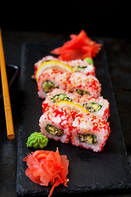 Comida tradicional japonesa - sushi, rollos y salsa sobre una mesa negra.