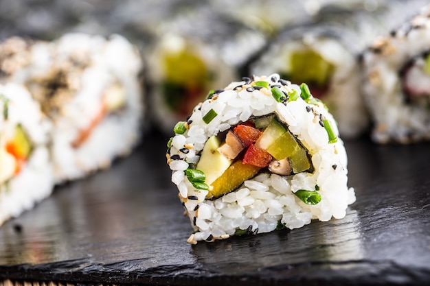 Comida tradicional japonesa sushi uramaki en pizarra.