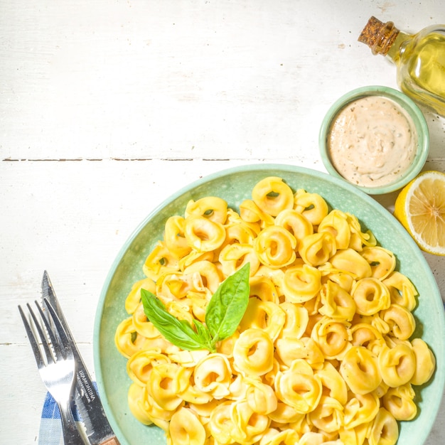 Comida tradicional mediterránea. Ravioles de tortellini de pasta italiana con queso feta, en el espacio de copia de la mesa de madera blanca