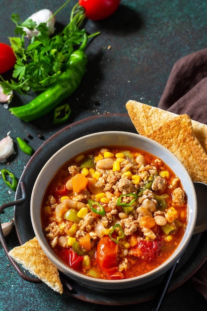 Comida tradicional mexicana Chili con carne carne picada con verduras en mesa de piedra oscura Espacio de copia