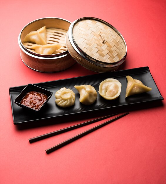 Comida tradicional momos de bola de masa hervida de Nepal servida con chutney de tomate sobre un fondo cambiante. Enfoque selectivo