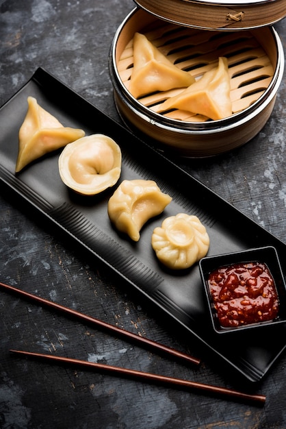 Comida tradicional momos de bola de masa hervida de Nepal servida con chutney de tomate sobre un fondo cambiante. Enfoque selectivo