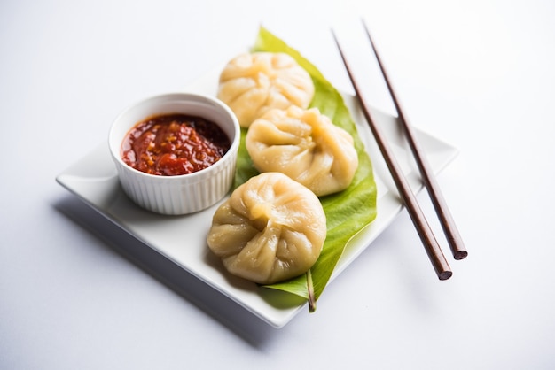 Comida tradicional momos de bola de masa hervida de Nepal servida con chutney de tomate sobre un fondo cambiante. Enfoque selectivo