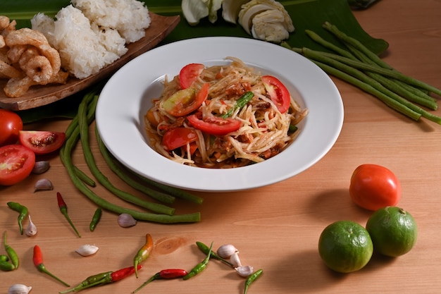 Comida tradicional tailandesa. Salada de mamão verde e ingredientes na mesa de madeira.