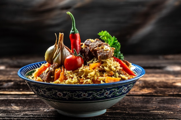 Comida tradicional uzbeka llamada pilaf. Arroz con carne, zanahoria y cebolla en plato con adornos orientales, cocina oriental uzbeka. Formato de banner largo. espacio para texto.