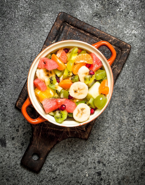 Comida tropical. Salada de frutas em uma tigela. Sobre fundo rústico.