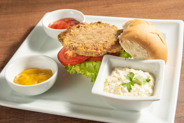 Comida vegan Hambúrguer vegano e molhos em um prato branco sobre foco seletivo de madeira