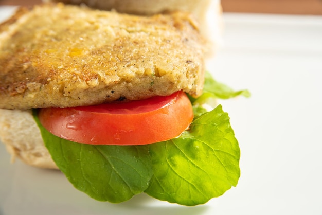 Comida vegan Hambúrguer vegano e molhos em um prato branco sobre foco seletivo de madeira