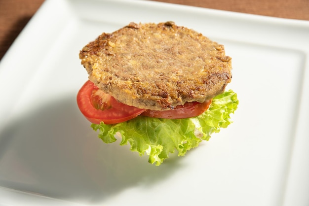 Comida vegana Hamburguesa vegana y salsas en un plato blanco sobre enfoque selectivo de madera