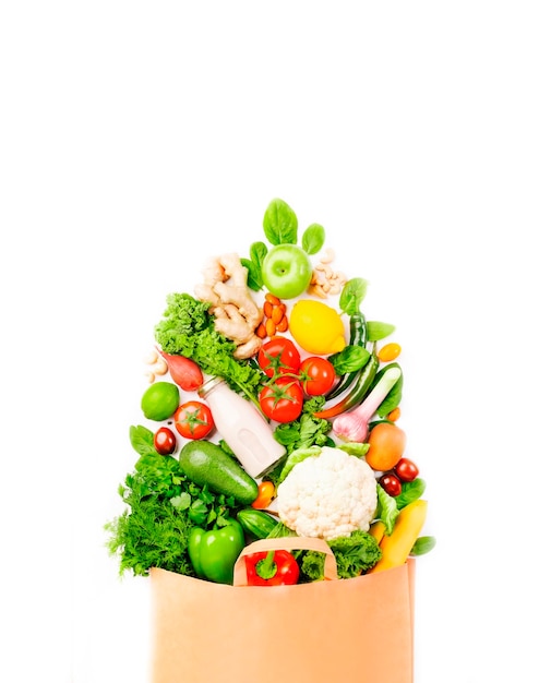 Comida vegana saludable en bolsa de papel completa verduras y frutas sobre fondo blanco copia espacio banner Compras supermercado comestibles y concepto de alimentación limpia