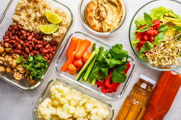 Foto comida vegana saludable en envases de vidrio, vista superior. arroz, frijoles, verduras, hummus y zumo.