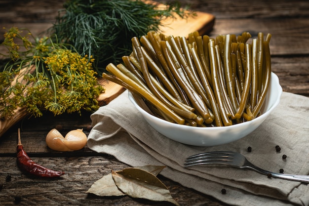 Comida vegana - talos de alho em conserva em uma superfície de madeira