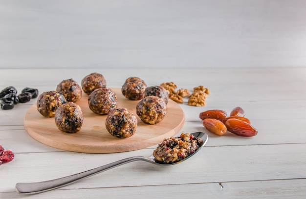 Comida vegetariana, bolas energéticas caseiras de nozes, tâmaras, ameixas, cranberries e mel no fundo branco com espaço de cópia