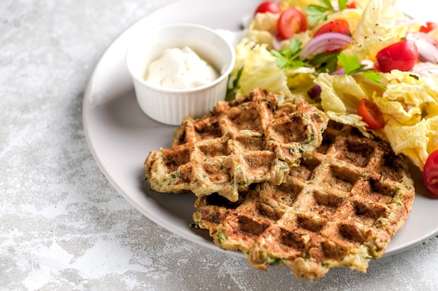 Comida vegetariana de waffles de vegetais com salada verde, tomate no prato