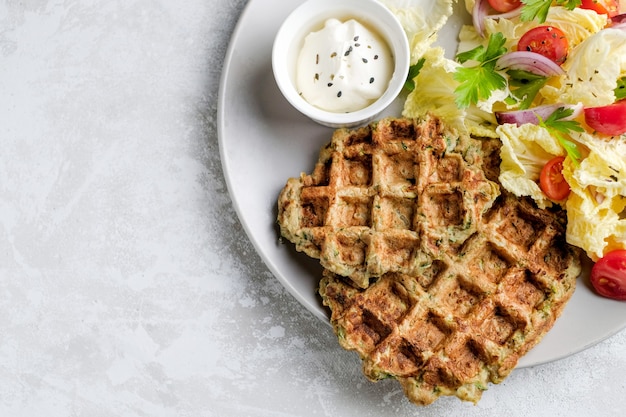 Comida vegetariana de waffles de vegetais com salada verde, tomate no prato