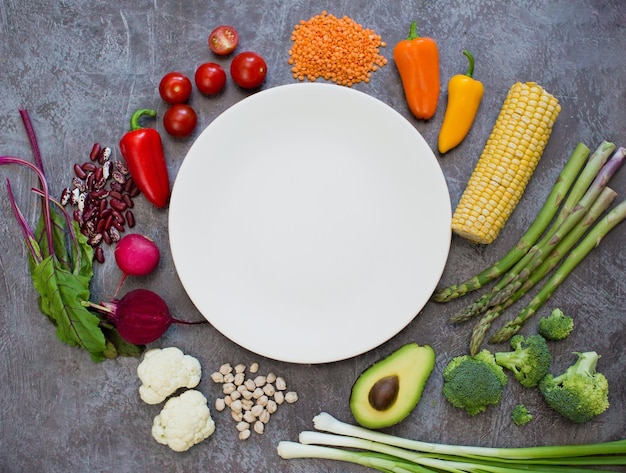 Comida vegetariana e prato branco Legumes frescos coloridos feijões e grão de bico em volta do prato branco vazio