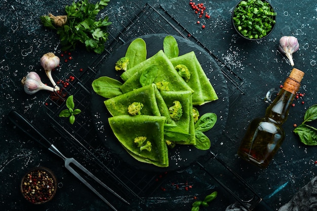 Comida vegetariana Panquecas de espinafre verde com legumes em uma placa de pedra preta Vista superior Espaço livre para o seu texto