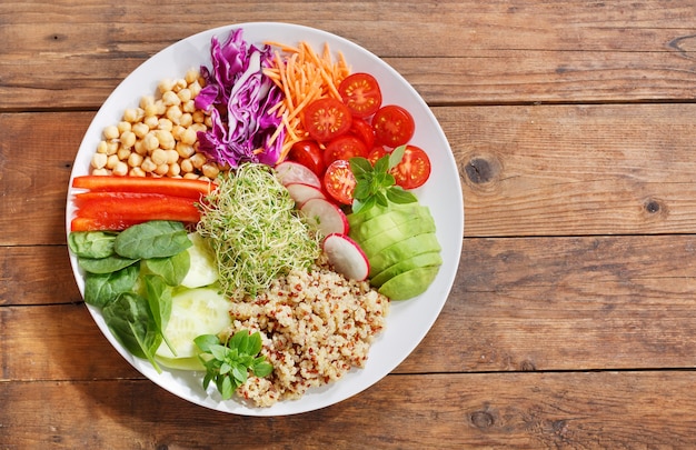 Comida vegetariana. prato de salada saudável com abacate, quinua, tomate, pimenta, espinafre, repolho, couve e grão de bico, vista superior