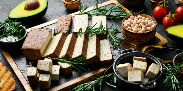 Comida vegetariana Queijo de tofu com alecrim cortado em pedaços em uma placa Sobre um fundo de pedra