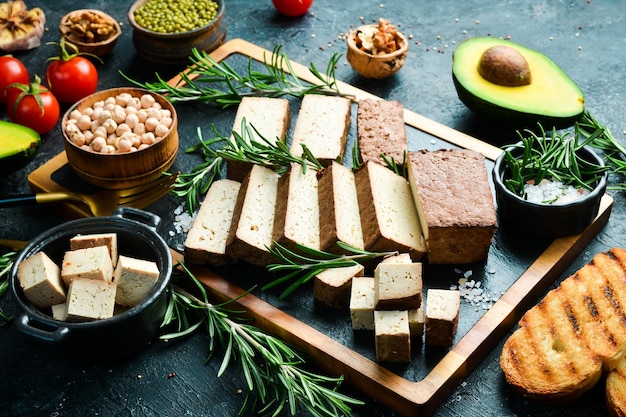 Comida vegetariana Queso tofu con romero cortado en trozos sobre una tabla Sobre un fondo de piedra