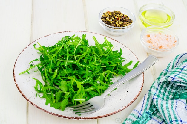 Comida vegetariana. Rúcula verde fresca sobre fondo blanco de madera.