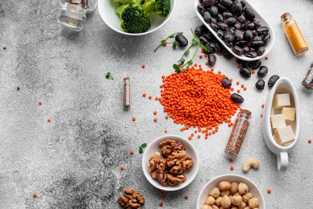 Comida vegetariana saudável em um fundo de concreto com espaço de cópia. Nozes, feijões, verduras e sementes