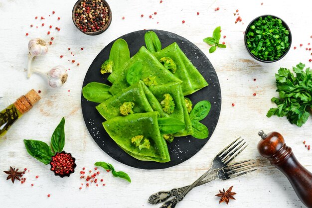 Comida vegetariana Tortitas de espinacas verdes con verduras en un plato de piedra negra Vista superior Espacio libre para el texto