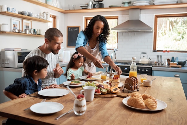 Comience el día con el desayuno Fotografía de una familia de cuatro personas disfrutando del desayuno juntos en casa