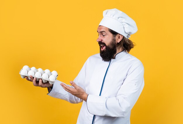 Cómo cocinar huevos. concepto de limpieza. hombre barbudo maduro usa gorro de cocinero. cocinero masculino listo para preparar la comida. hipster brutal en delantal va a cocinar comida. tiempo para comer. horneado feliz.