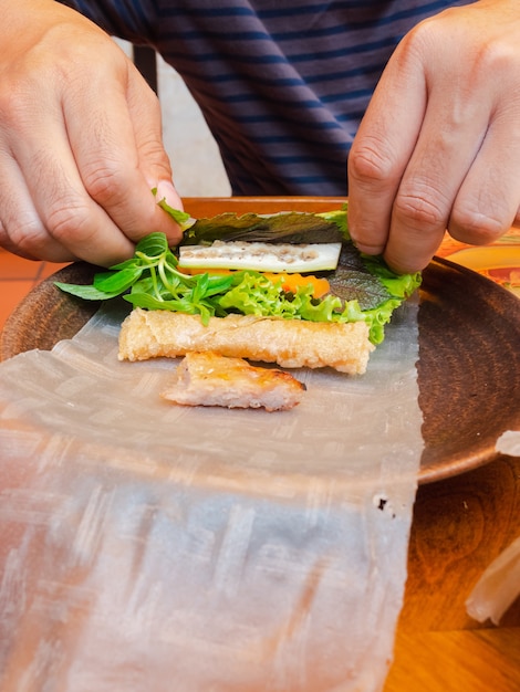 Foto cómo comer, envoltura a mano de carne a la parrilla vietnamita o envoltura de albóndigas con verduras y salsa dulce (nham neung)