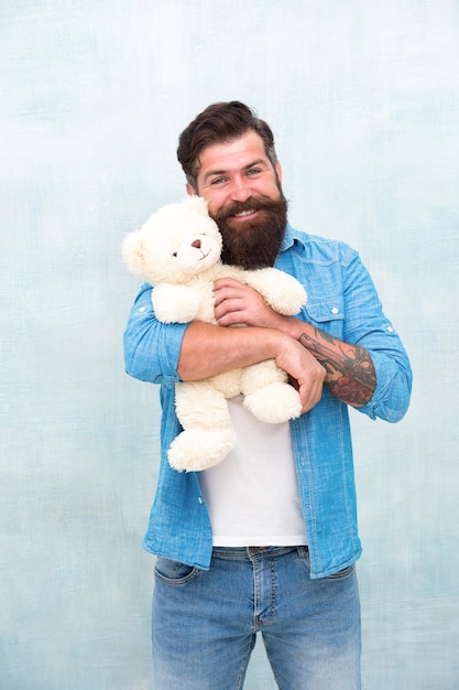 Como cuidar de alguém. Conceito de loja de brinquedos. Feliz aniversário. Hipster bonito segura brinquedo adorável urso. Dia dos Namorados. Presente para o seu parceiro. Homem com cara feliz de barba carrega o brinquedo do presente. Humor lúdico.