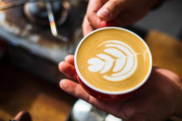 Foto cómo hacer café latte art por barista enfocado en leche y taza de café en la cafetería