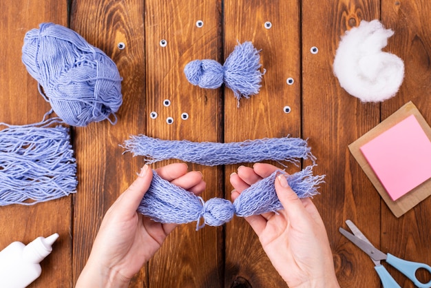 Cómo hacer un lindo pájaro de hilo para decoración. Proyecto de arte infantil. Concepto de bricolaje. Las manos están hechas de hilos azules de una paloma azul. Instrucciones fotográficas paso a paso.