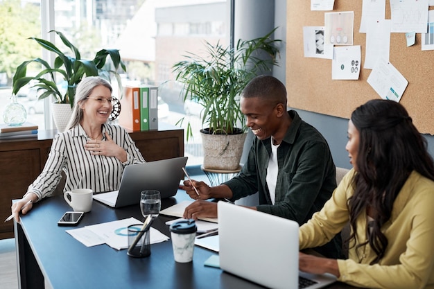 Como un ladrón, se necesita tiempo para ser este gran Toma de un grupo de empresarios haciendo una lluvia de ideas y usando una computadora portátil en una oficina moderna