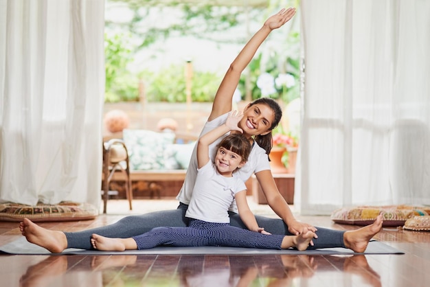 Como madre, como hija Retrato de una joven y alegre madre e hija haciendo una pose de yoga juntas mientras estiran los brazos hacia un lado
