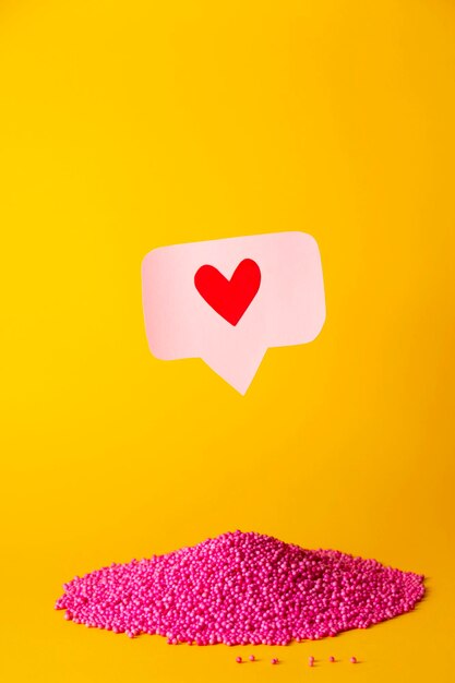 Foto como o ícone do coração em um alfinete rosa sobre o slide de bolas cor-de-rosa muitos emoji corações em redes sociais conceito