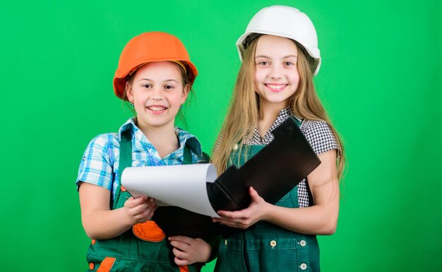 ¿Cómo puedo ayudarlos, niñas pequeñas, reparando juntas en el taller? Inspector de capataz Reparación Día del trabajo 1 de mayo proyecto escolar Niños felices Niños pequeños con casco con tableta