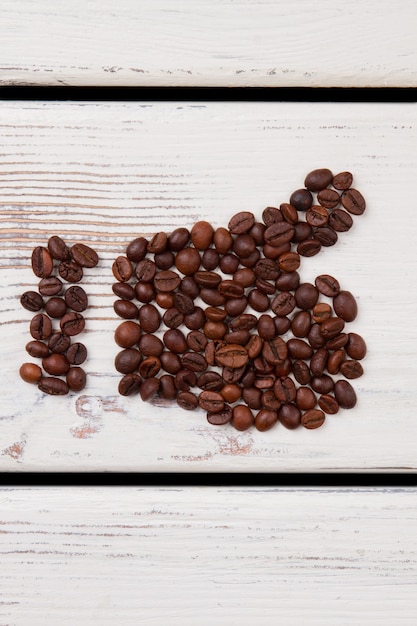 Como símbolo de granos de café. Pulgar hacia arriba en madera limpia.