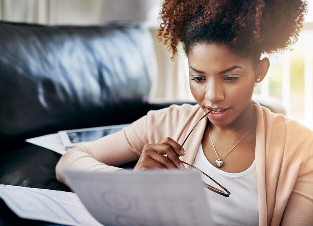 ¿Cómo se ve mi progreso financiero? Foto de una mujer joven que revisa su papeleo en casa.