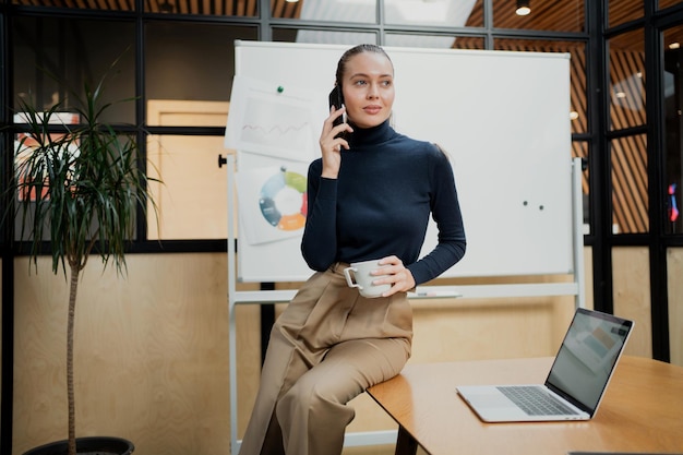 Cómoda ropa de oficina con estilo, una mujer joven muy hermosa sostiene un teléfono en sus manos