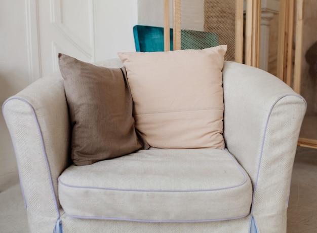 Cómoda silla tapizada con almohadas en el interior del apartamento.