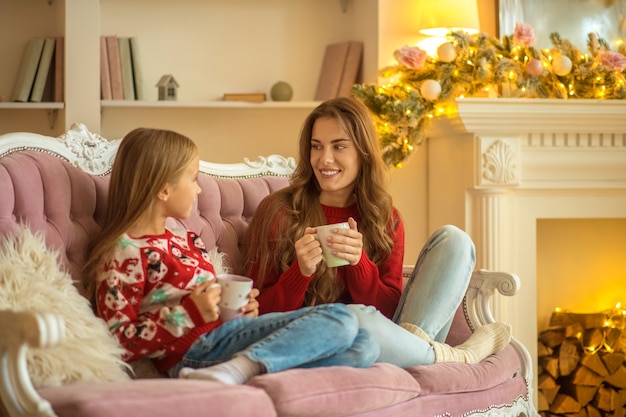 Comodidad. Mamá e hija sentadas en el sofá y sintiéndose bien