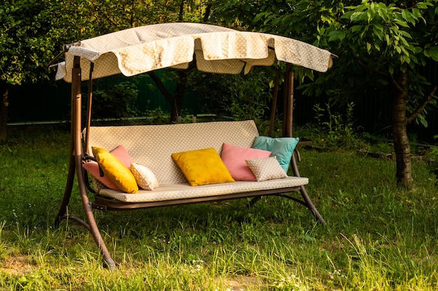 El cómodo columpio con almohadas en el patio trasero en verano.